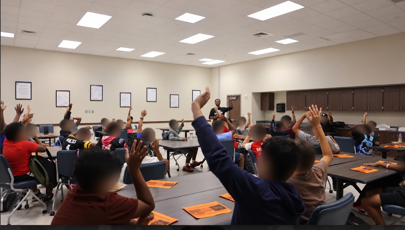 Coach leading an engaged workshop of middle and high school students with hands raised
